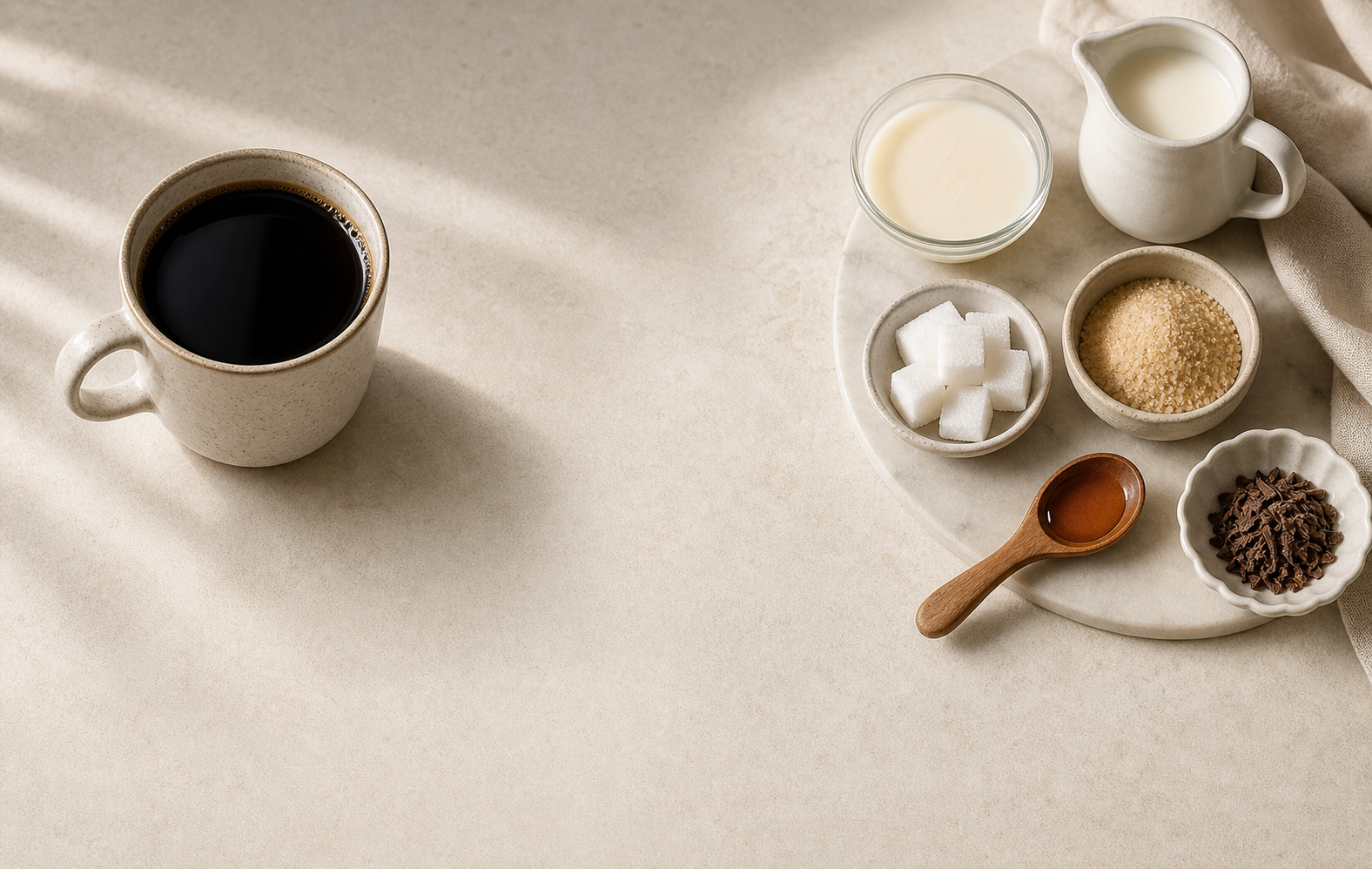 A black coffee cup separated from cream, sugar, and other add-ins on a clean morning surface.